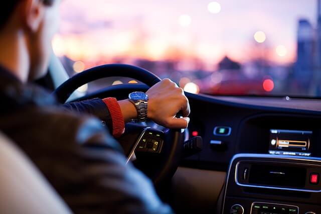 gps do samochodu w służbowym aucie prowadzonym przez eleganckiego mężczyznę jadącego w kierunku zachodu słońca