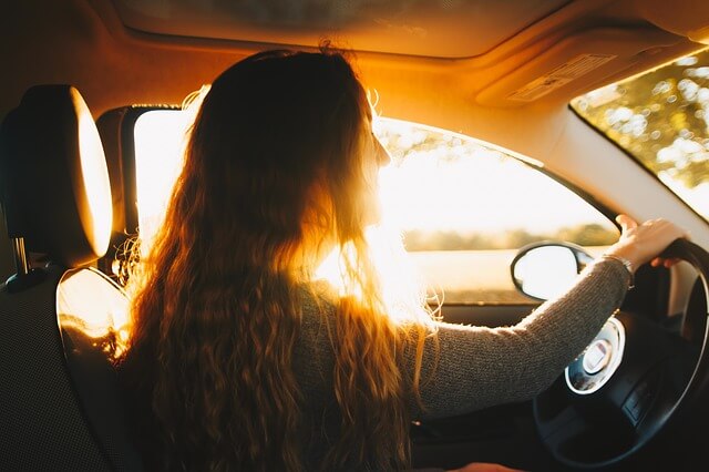 młoda kobieta z długimi włosami w aucie jedzie podczas zachodu słońca używając w swoim samochodzie auto gps