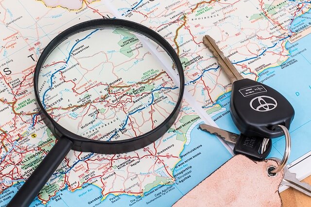 rozłożona mapa na której leży lupa i czarne kluczyki od auta