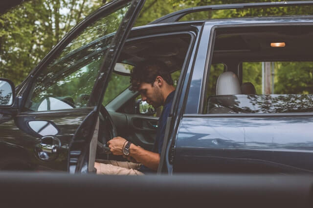 młody kierowca siedzący na przednim fotelu w samochodzie montuje gps do auta w swoim samochodzie