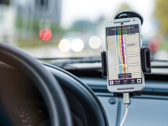 telefon komórkowy przymocowany na uchwycie w samochodzie z włączoną lokalizacją gps