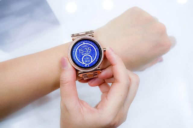 Inteligentny zegarek dla dziecka czyli smartwatch w złotym kolorze na dłoni dziewczynki, wskazujący godzinę 15:35