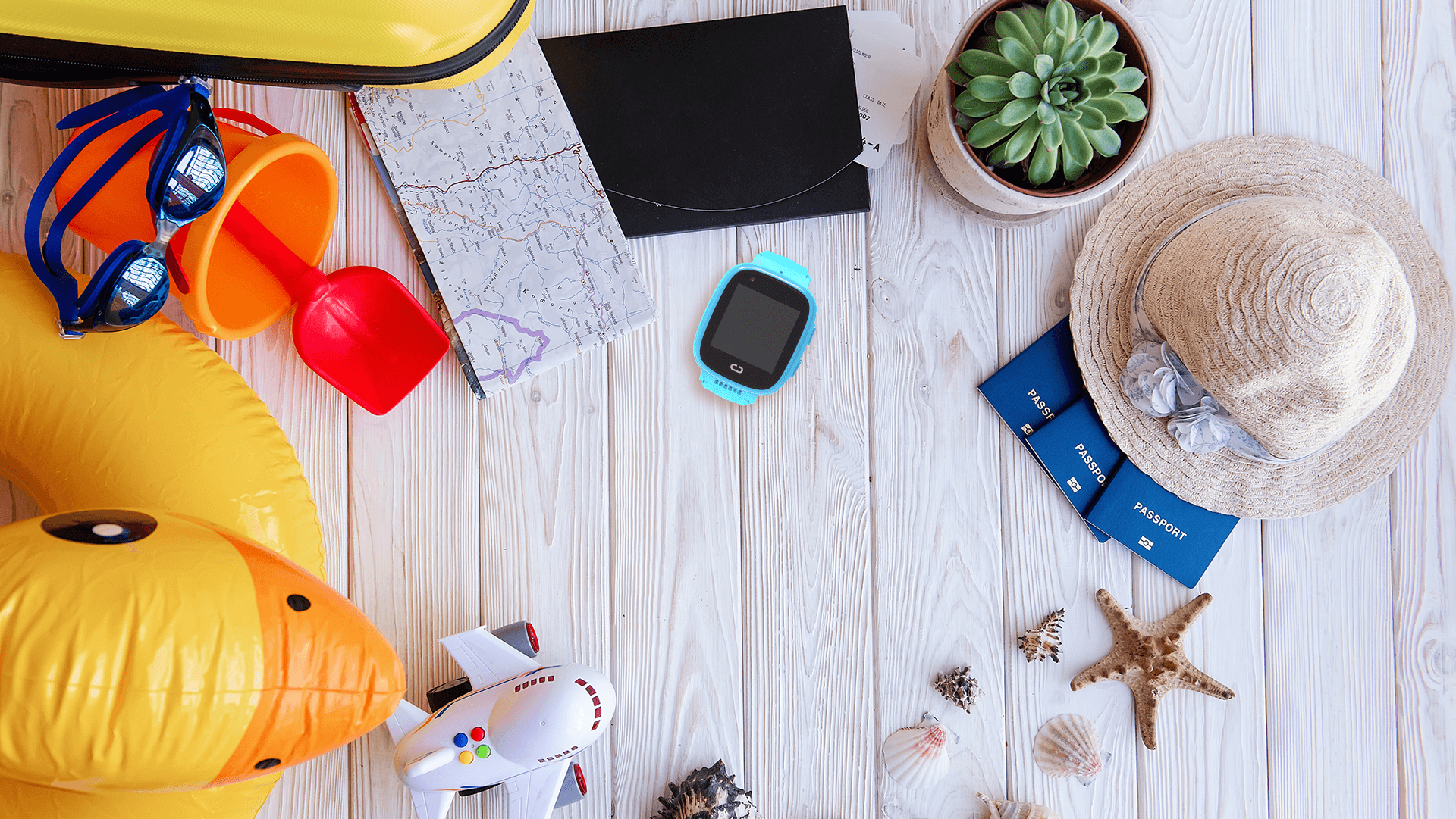 Rozłożone rzeczy, które trzeba spakować dla dziecka na wakacje, czyli smartwatch, akcesoria na plażę, kapelusz