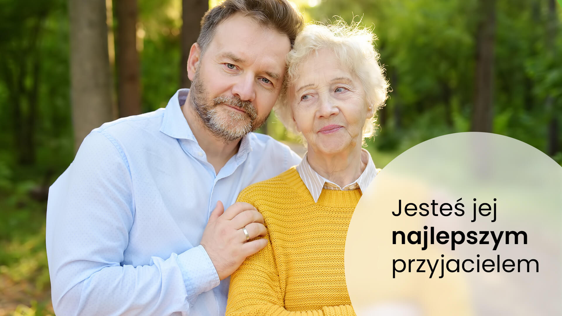 Mężczyzna w średnim wieku ubrany w niebieską koszulę przytulający starszą kobietę, swoją mamę ubraną w żółty sweter