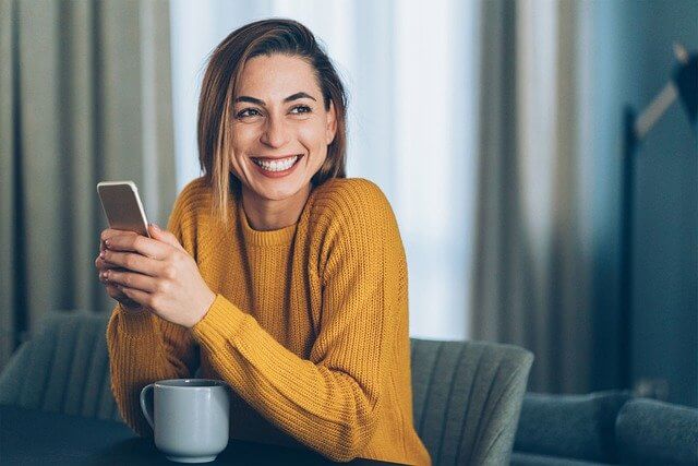 Uśmiechnięta kobieta sprawdza kto dzwonił do jej dziecka na telefonie