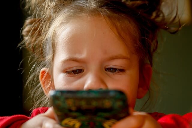 Telefon dla dziecka dziewczynki patrzącej w ekran smartfona